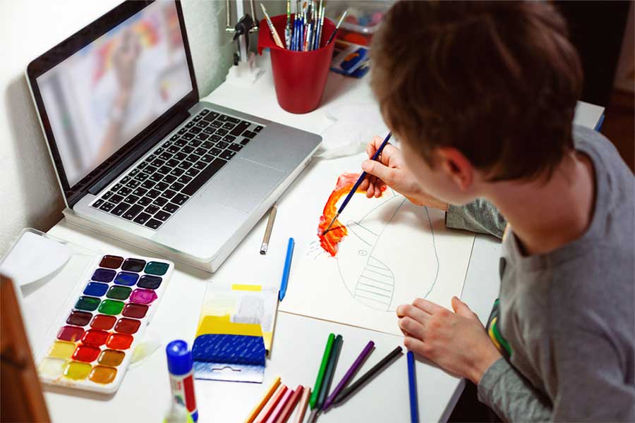 A student paints a whale during an online lesson